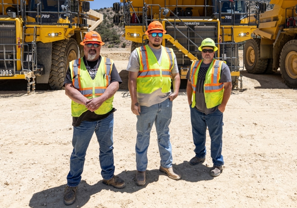 Group of construction workers in front of equipment line-up